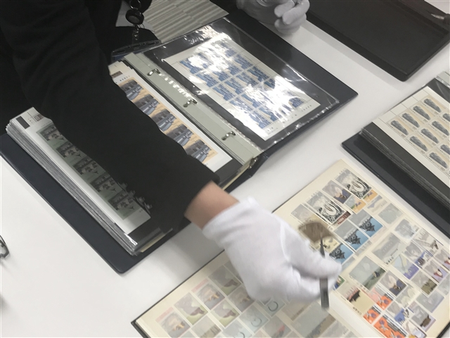 切手をピンセットでつまむ